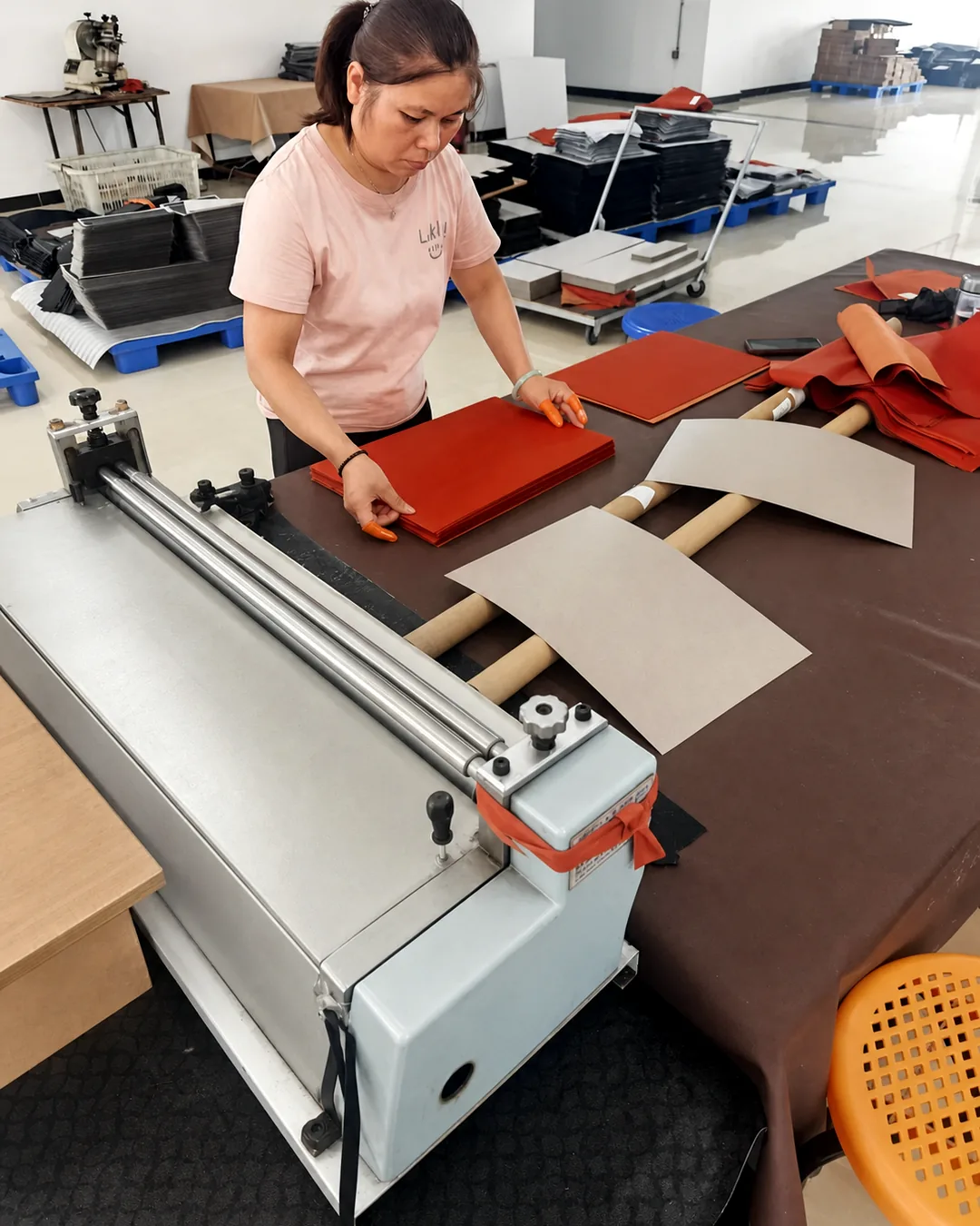 Operator laminating red leather panels on a roller machine