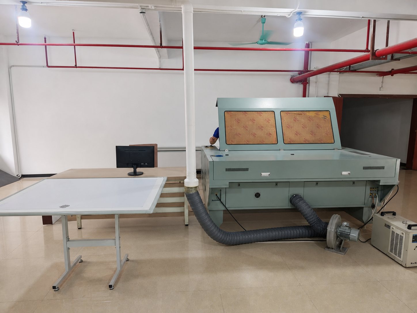 Laser cutting bed with fume extraction and a layout table on DINLEEY's production line.
