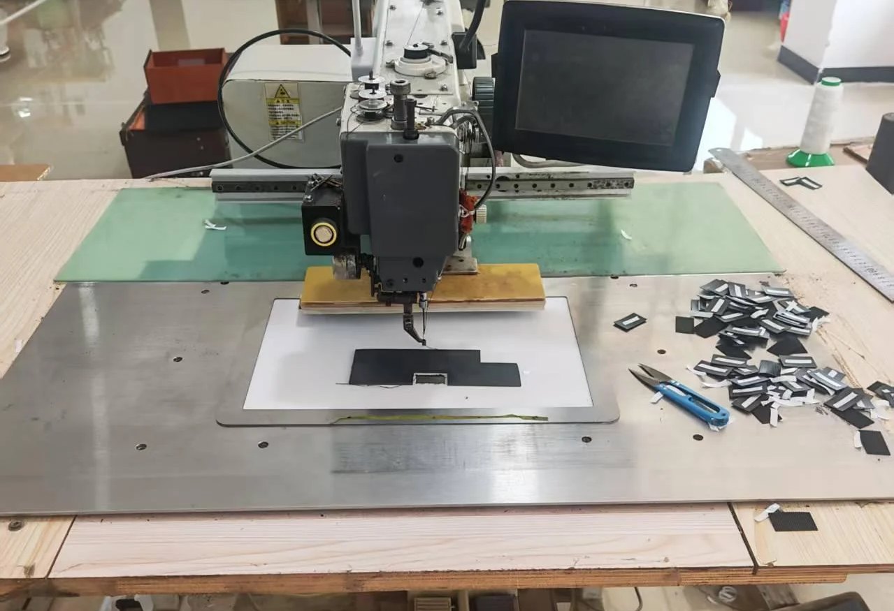 Programmable pattern sewing machine with a control screen and a template holding a small black part.